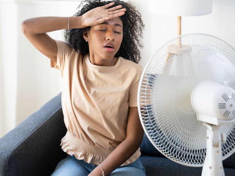 A black woman at home trying to cool down in front of the fan