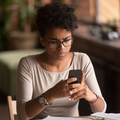 A black woman holds up her smartphone with a confused look on her face