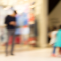 A blurred image of a man standing around children in a public space