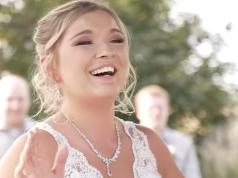 A blushing bride happily raises her arms