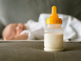 A bottle of milk and a baby sleeping