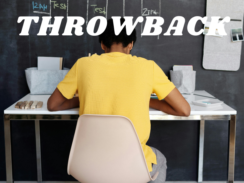 A boy at his desk doing work wearing a yellow shirt