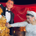 A bride and groom decorate their chicken wedding cake with sauce