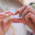 A bride and groom hold their wedding rings together