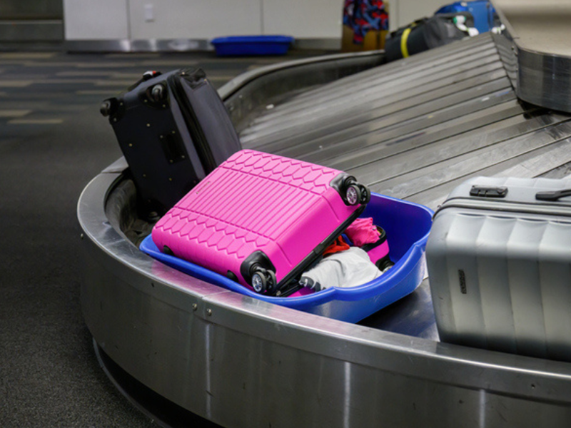 A broken opened suitcase moving through the conveyor belt of the baggage claim