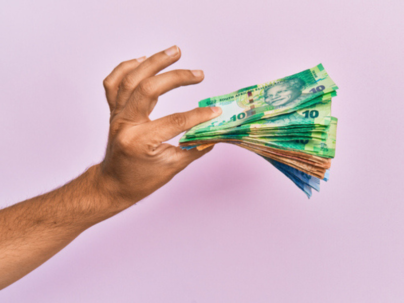 A brown coloured hand holding South African rand