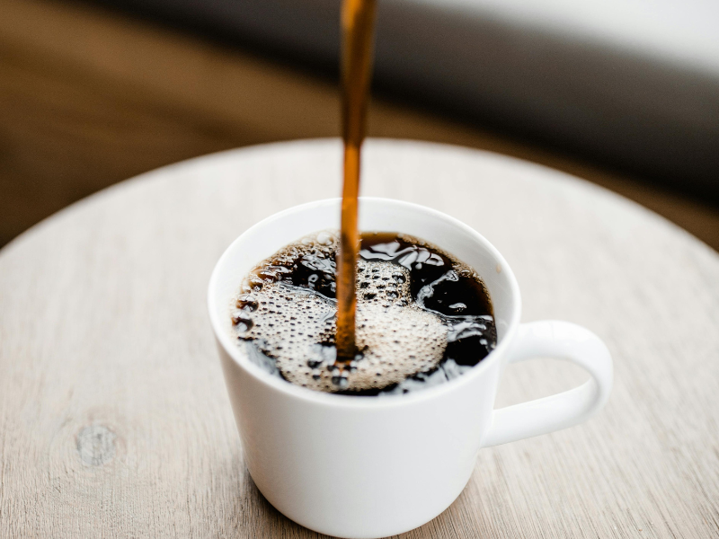 A ceramic mug being filled with coffee