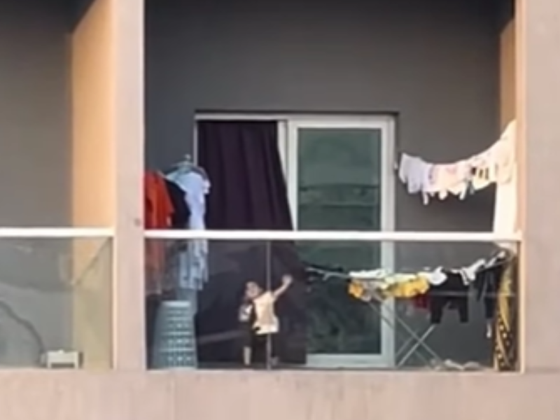 A child throws a piece of clothing over the balcony
