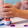 A child using glue stick to stick shape cutouts on paper