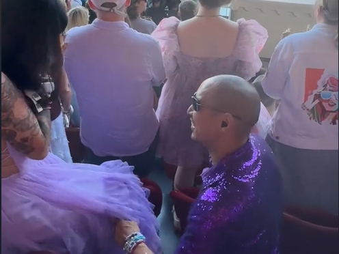 A couple wearing purple get engaged at The Era's Tour