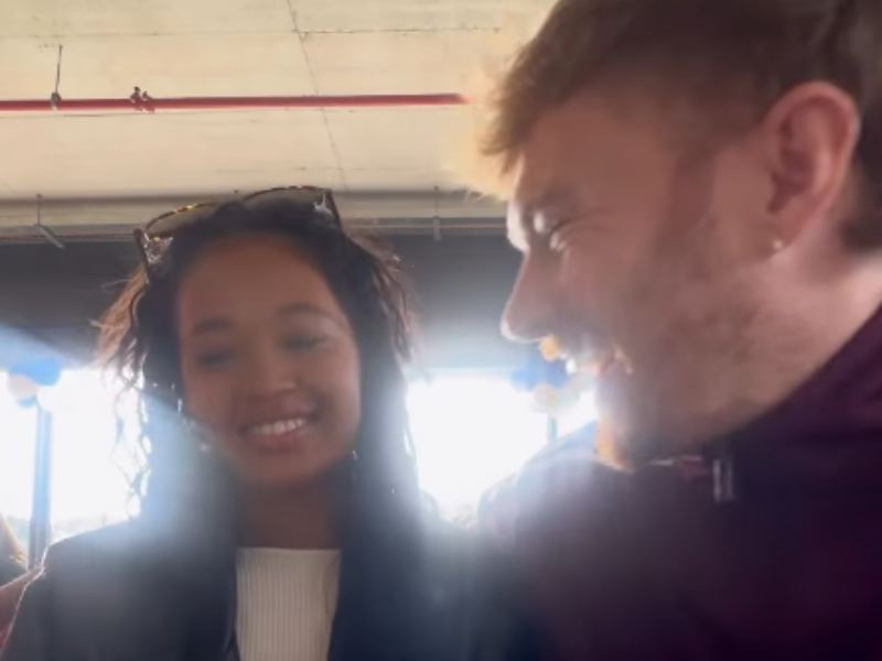 A couple laugh with one another at an outdoor eatery