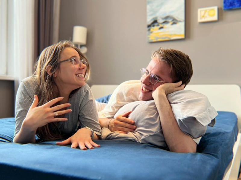 A couple laughing together while lying on the bed