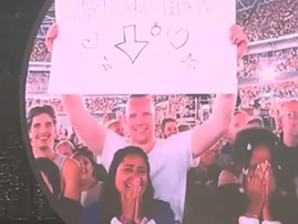 A couple with a sign on the jumbotron at a Coldplay concert