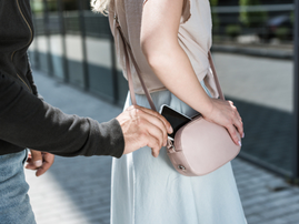 A criminal pickpocketing a smartphone from a womans handbag