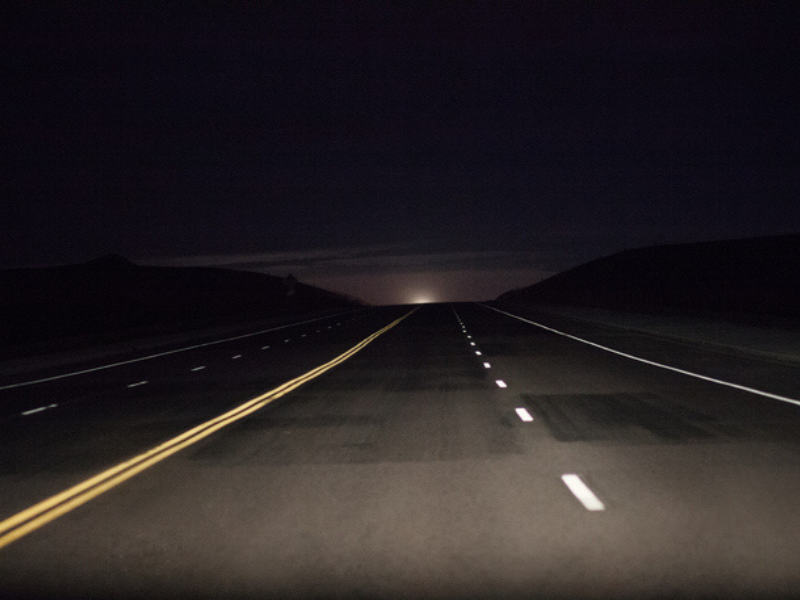 A dark road with headlights