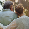 A daughter hugs her father lovingly in a park