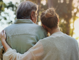 A daughter hugs her father lovingly in a park