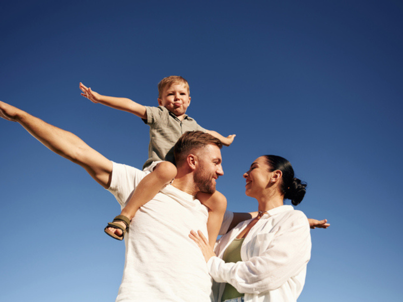 A family enjoy time outdoors with their arms spread