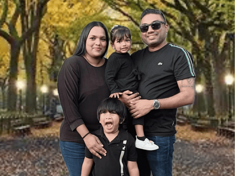 A family of four dressed in black on a road with arched trees
