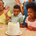 A family singing and celebrating a childs birthday with a cake