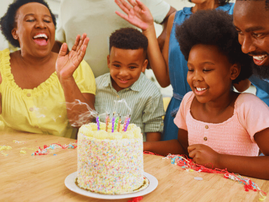 A family singing and celebrating a childs birthday with a cake