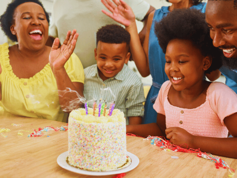 A family singing and celebrating a childs birthday with a cake