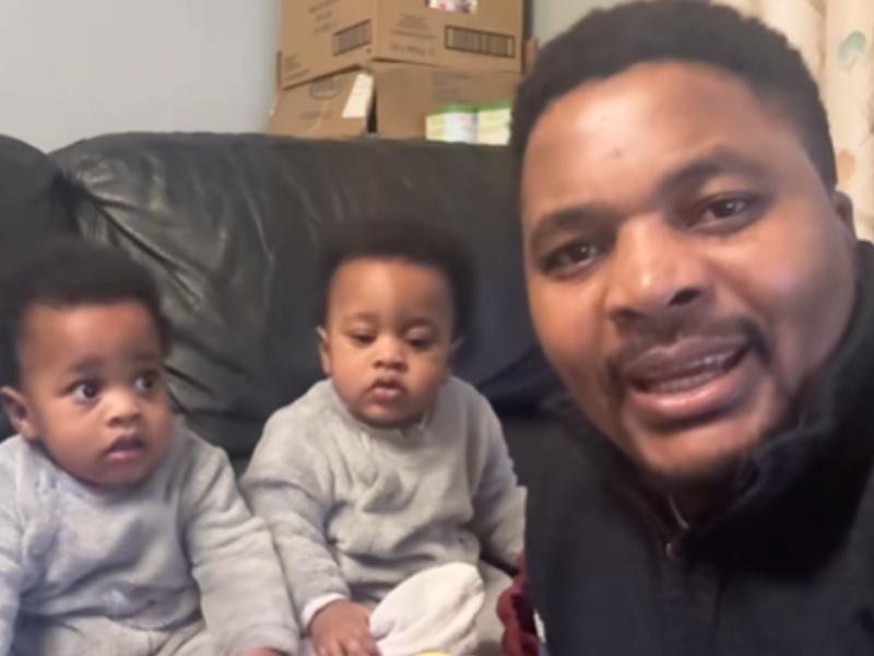 A father sits with his twin identical babies