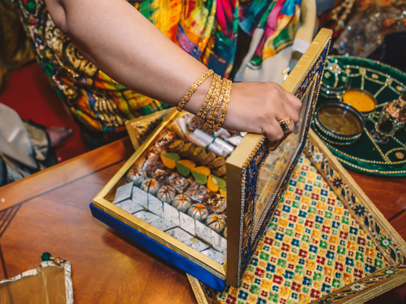 A female hand opening up a Diwali box filled with sweet treats