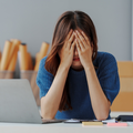 A female worker holds her face in dismay in her workplace