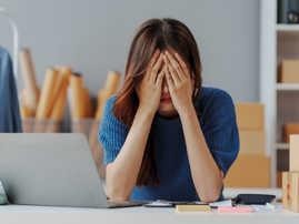 A female worker holds her face in dismay in her workplace