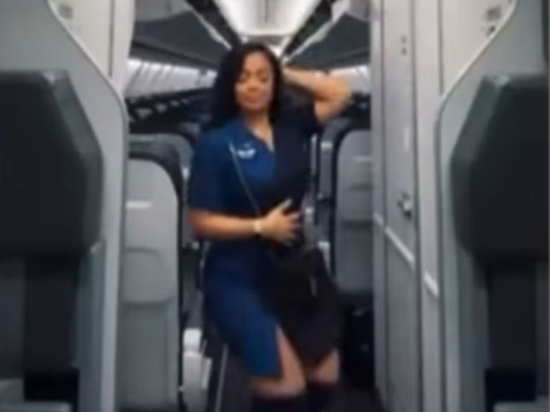 A flight attendant dancing during the aisle of an empty plane