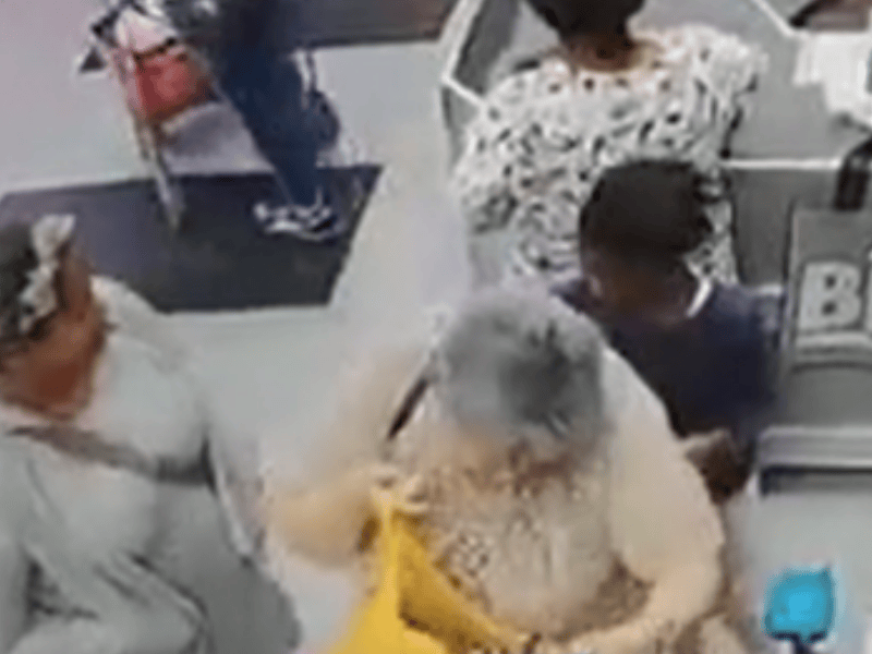 A girl steals something out of an elderly womans handbag at a grocery store