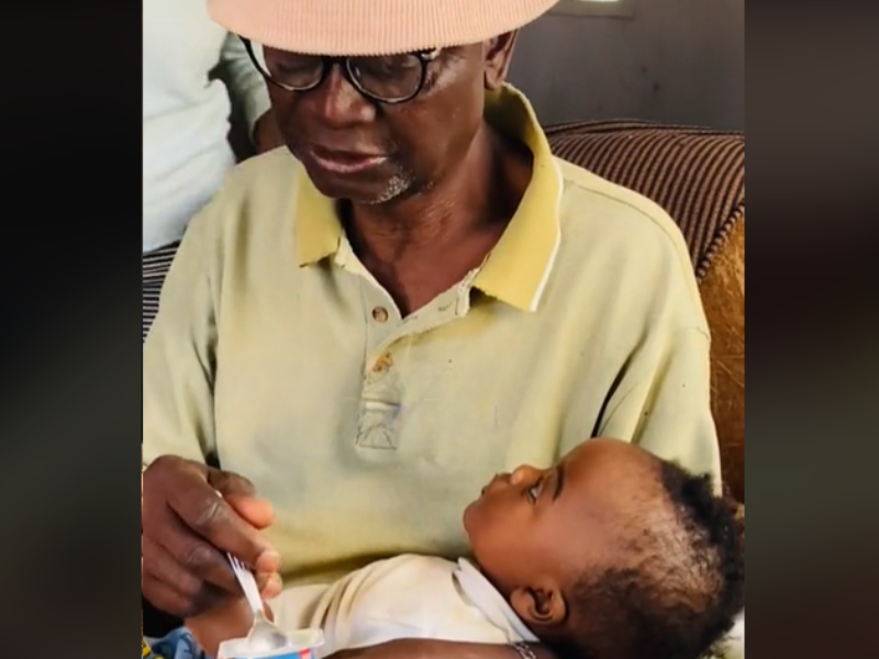A grandfather feeding his grandbaby yoghurt