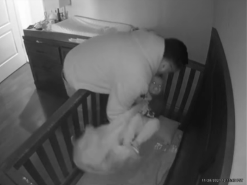 A grandfather laying his granddaughter in her crib
