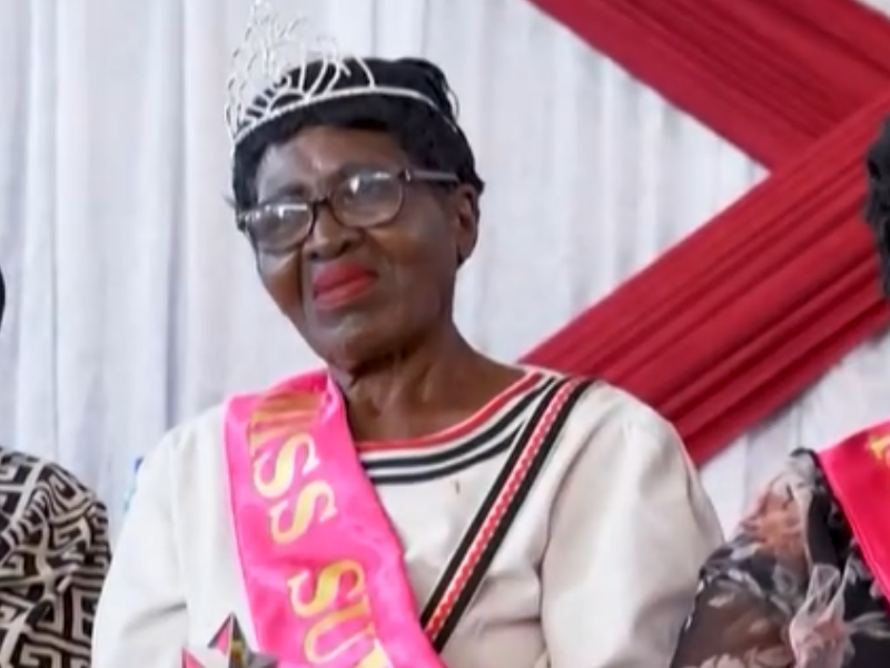 An elderly woman wear a crown on and sash at a beauty pageant