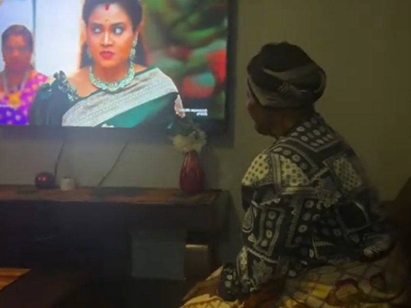A grandmother sitting on her couch watching her TV shows