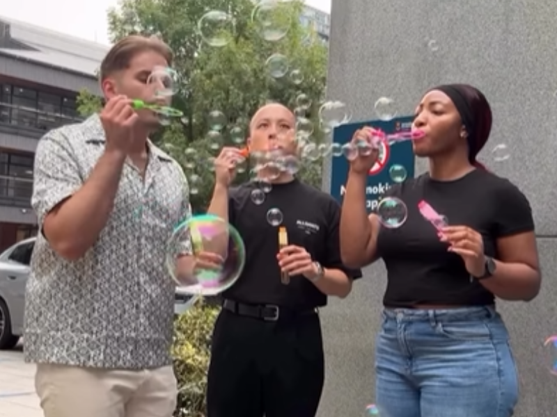 A group of coworkers blow bubbles outside their office
