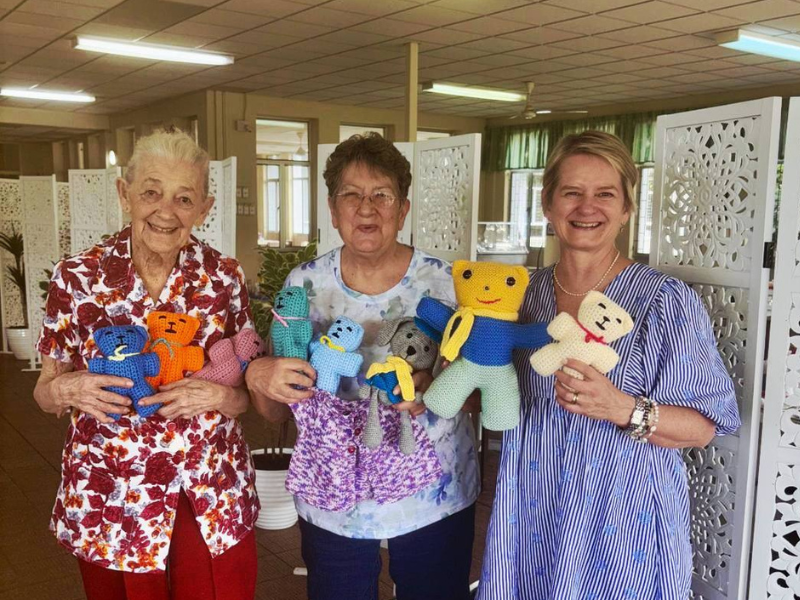 A group of ladies hold up crocheted teddies