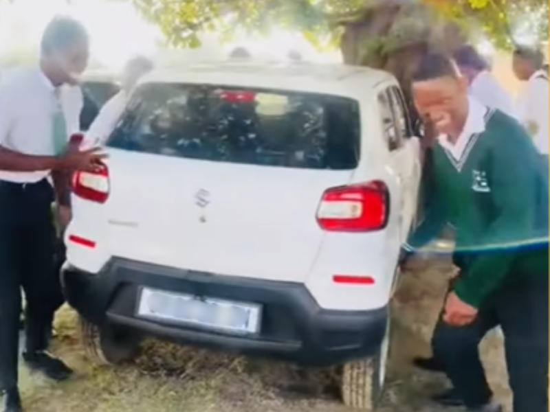 A group of students carry and move their teachers car