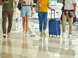 A group of travelers walking in the airport with their luggage