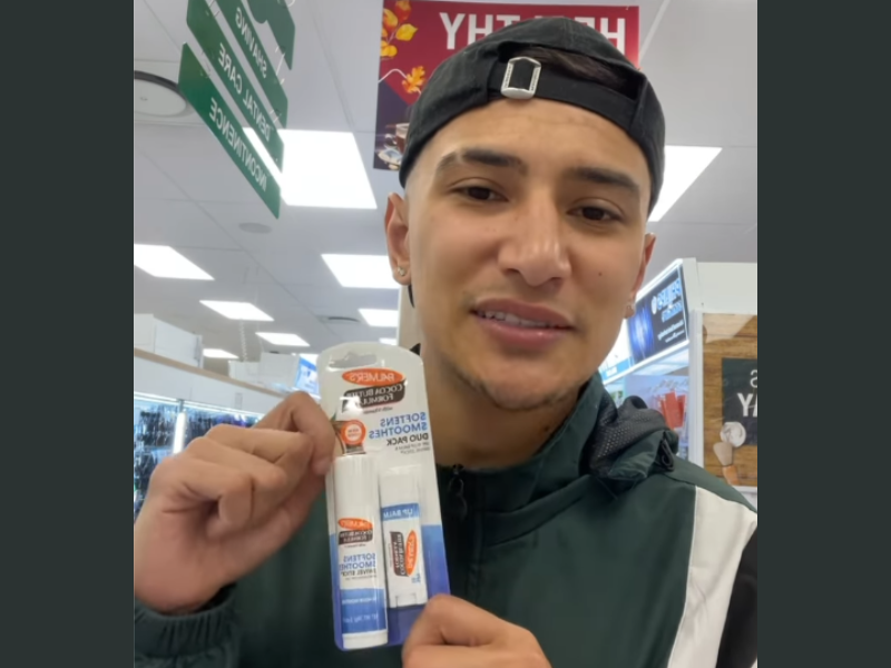 A guy holding up a lip product that he found at a store