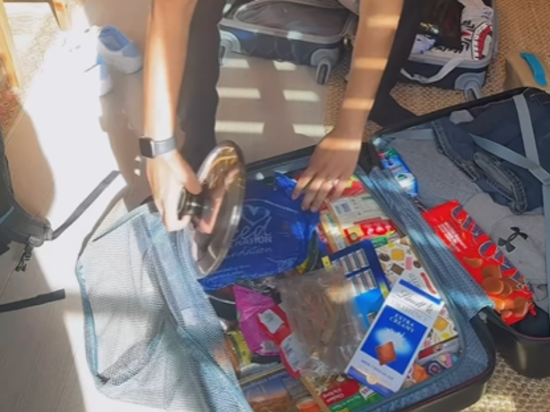 A guy opens up his suitcase to reveal South African snacks and food