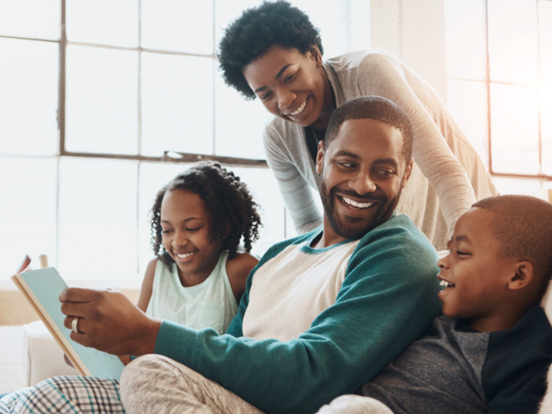 A happy family reading a book together on the couch