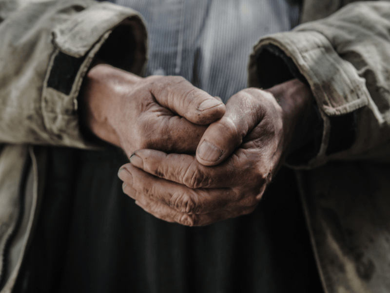 A homeless mans hands are messed with dirt