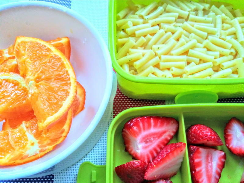 A homestyle school lunch with pasta and fruit