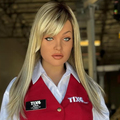 A humanoid robot with blonde hair wearing a red waistcoat