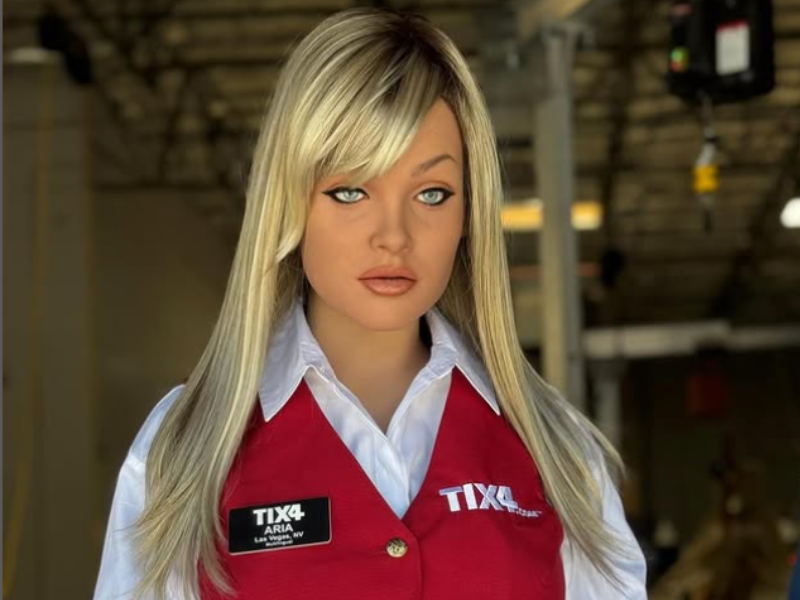 A humanoid robot with blonde hair wearing a red waistcoat