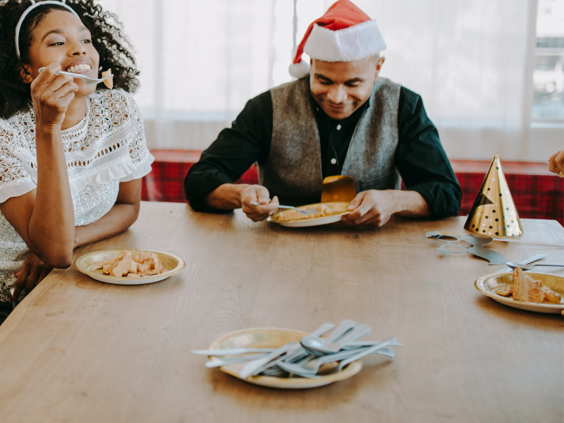 A lady and a man seated at a table eating at Christmas party