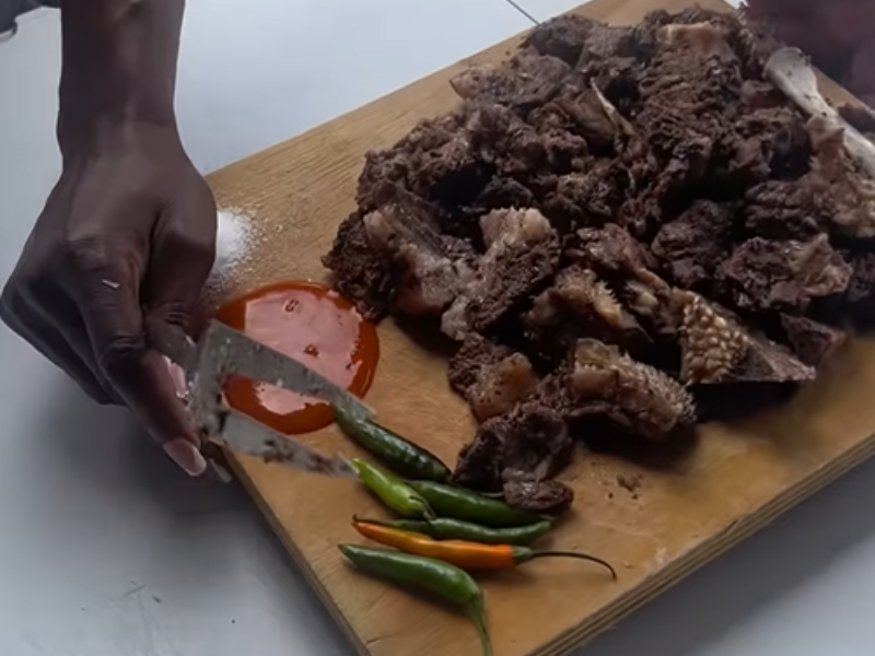 A woman serves up a wooden board filled with meat and sauce