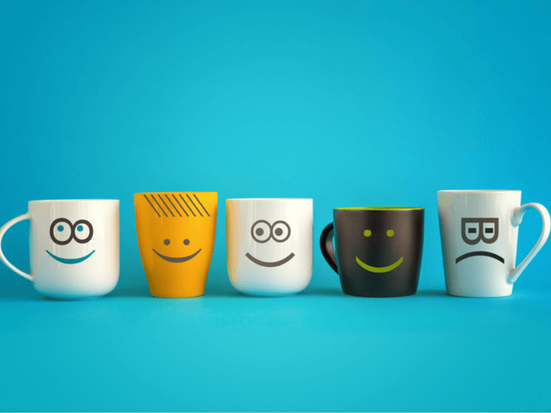 A line of coffee mugs with different emoticons on them